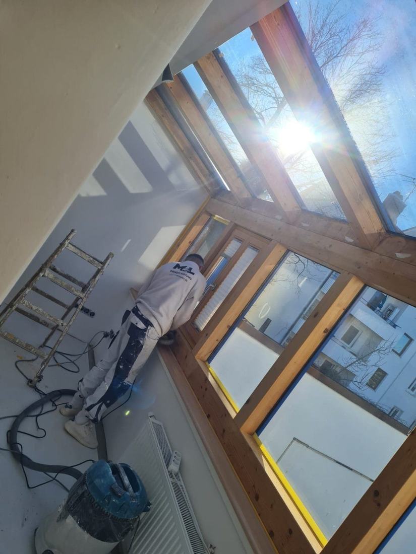 MEL-Mitarbeiter schleift die Holzrahmen in einem sonnigen Wintergarten